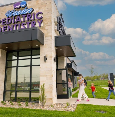 Exterior of Weeder Pediatric Dentistry with modern signage and a family walking in.