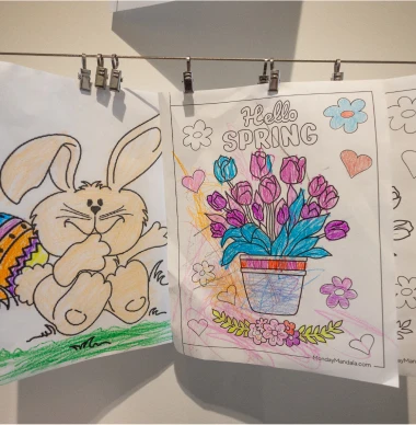 Children's spring-themed coloring pages hanging on display.