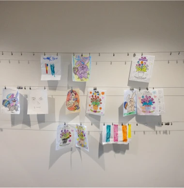 Wall display of children's colorful spring-themed drawings and artwork.