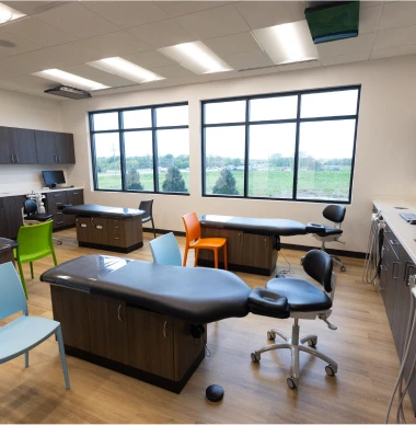 Modern pediatric dental exam room with colorful chairs and treatment stations.