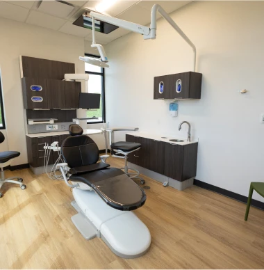 Modern dental exam room with chair, equipment, and cabinetry