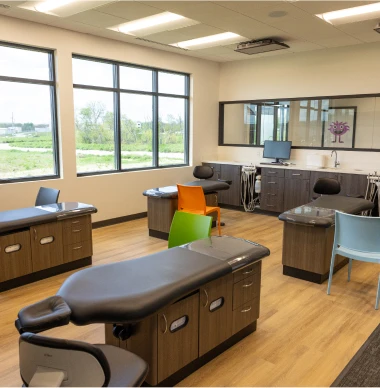Modern pediatric dental exam room with colorful chairs and workstations